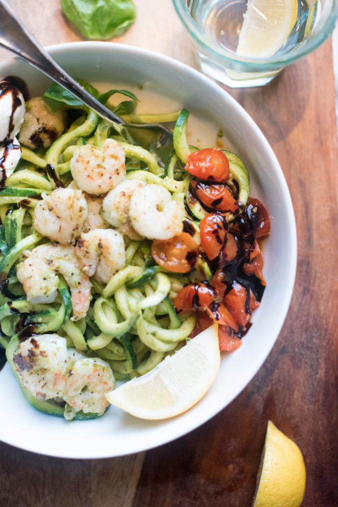 Shrimp and Zucchini noodles tossed in a delectable pesto with fresh burrata cheese and oven roasted tomatoes. Everything gets drizzled with a sweet balsamic glaze. Best part: It can be made in 20 minutes. | FirstandFull.com