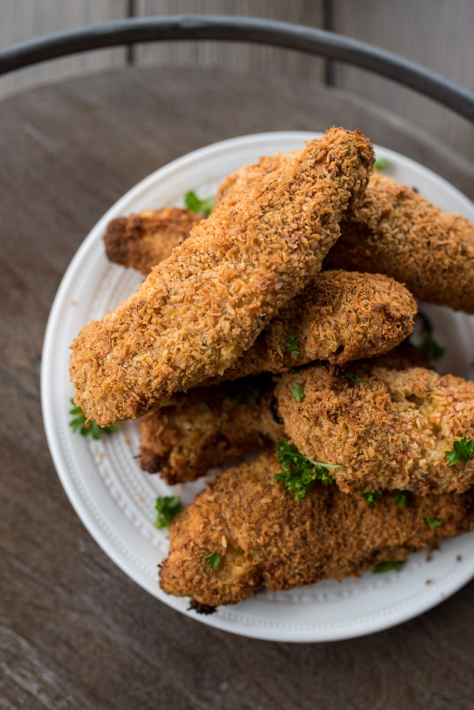 Crispy, Whole30 Chicken tenders breaded with seasoned almond flour, unsweetened coconut and BAKED to perfect! Delicious when dunked in dairy- free, roasted garlic ranch and are freezer friendly! The whole family will love these Whole30 Chicken Tenders.