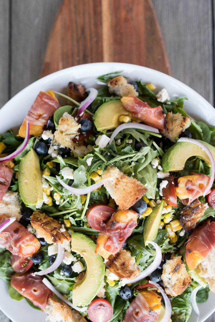 This Grilled Prosciutto wrapped peach panzanella salad is a light and delicious summer salad with grilled prosciutto-wrapped peaches, sweet blueberries, crumbled feta, grilled sourdough and charred corn.